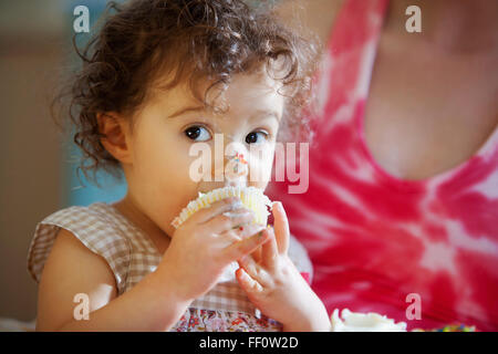 Messy baby girl eating cupcake Stock Photo