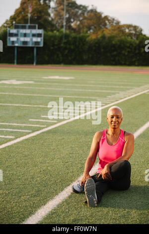 Woman stretching on football field Stock Photo
