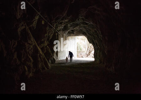 Caucasian mother and daughter walking in cave Stock Photo