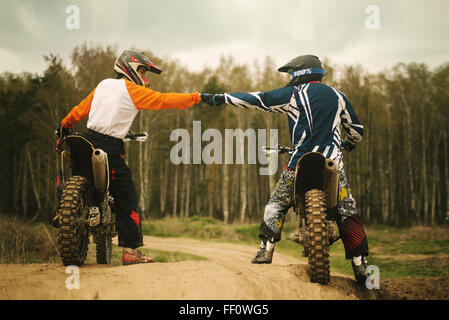 Caucasian men bumping fists on dirt bikes Stock Photo