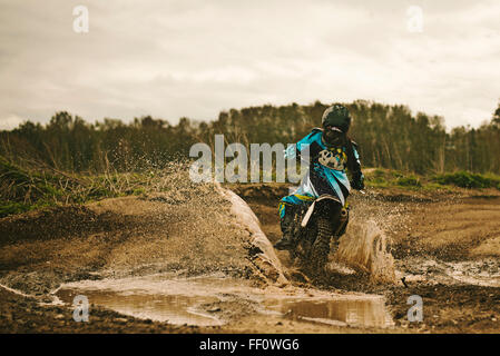 Caucasian man riding dirt bike in puddle Stock Photo