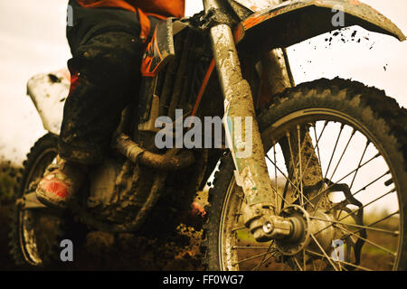 Close up of man riding muddy dirt bike Stock Photo