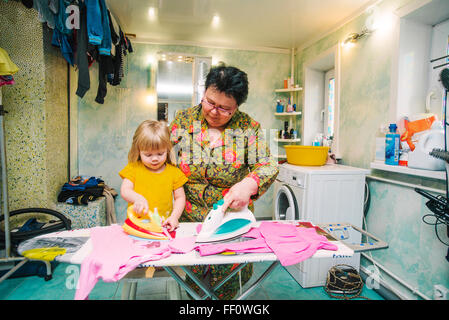 Caucasian grandmother and granddaughter ironing laundry Stock Photo