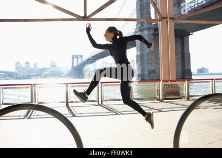 Caucasian runner jumping on waterfront, New York, New York, United States Stock Photo