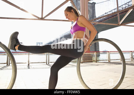 Caucasian runner stretching on waterfront, New York, New York, United States Stock Photo