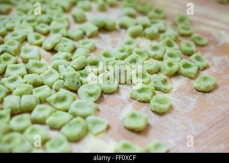 Green gnocchi scattered on a wooden counter top. Stock Photo