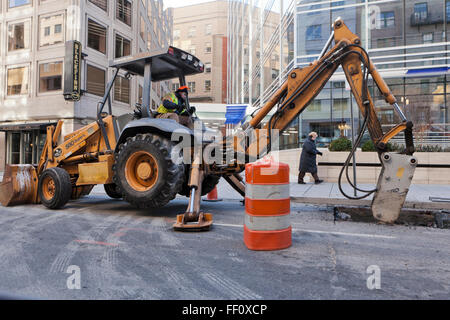 Backhoe with jackhammer attachment working in urban roadway - USA Stock Photo