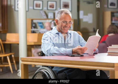 Caucasian man reading in library Stock Photo