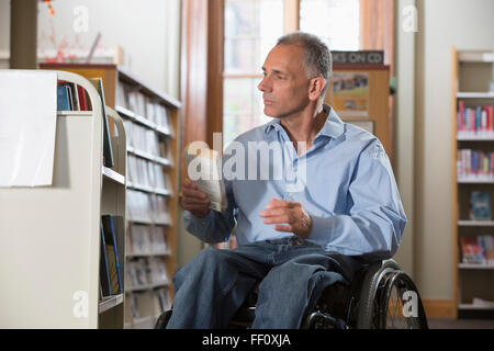Caucasian man holding book in library Stock Photo