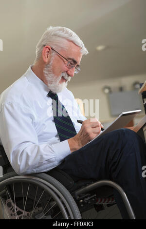 Caucasian businessman writing on notepad in office Stock Photo