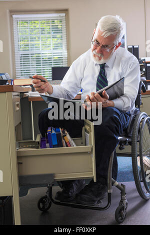 Caucasian businessman reading binder at desk Stock Photo