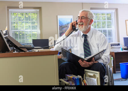 Caucasian businessman talking on phone at desk Stock Photo