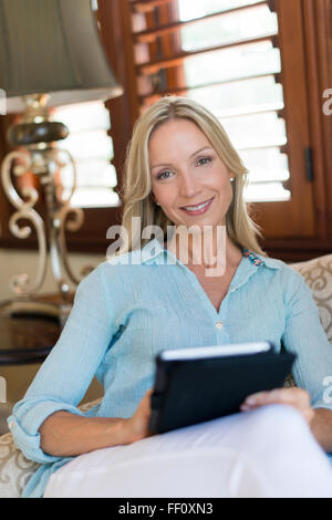 Caucasian woman using digital tablet in armchair Stock Photo