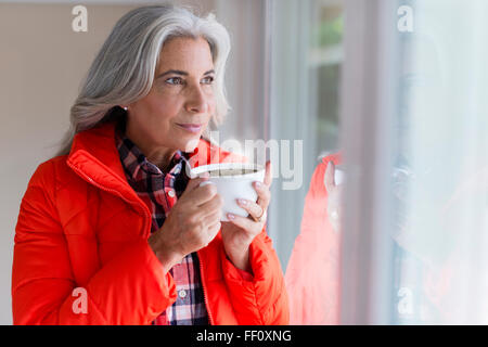Caucasian woman drinking coffee in window Stock Photo