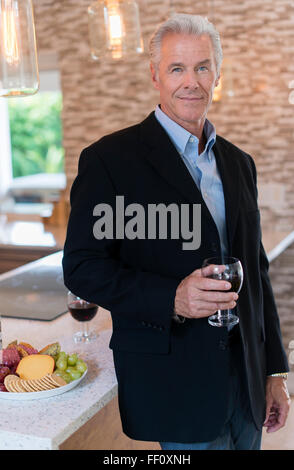 Caucasian man drinking wine in kitchen Stock Photo