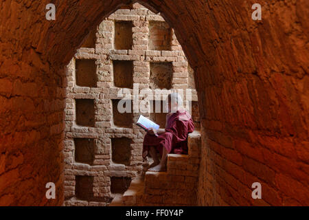 A young monk reading in the temples of Bagan, Myanmar Stock Photo
