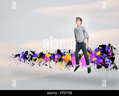Mixed race boy jumping with paint splatters Stock Photo
