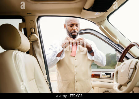 Black man tying bow tie in car Stock Photo