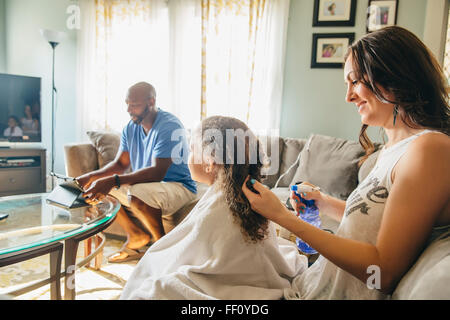 Mother styling hair for daughter in living room Stock Photo