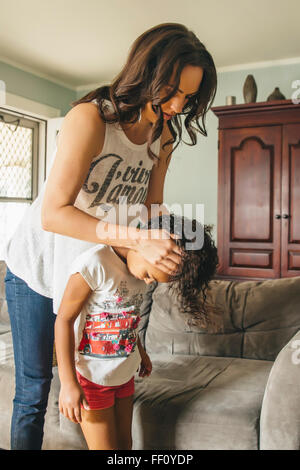 Mother styling hair for daughter in living room Stock Photo