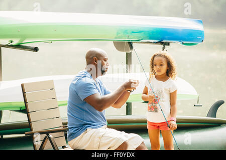 Father baiting fishing hook for daughter at lake Stock Photo