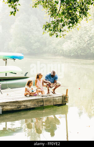 Father and daughters fishing in lake Stock Photo