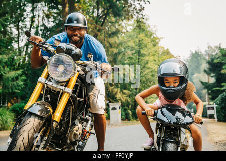 Father and daughter sitting on motorcycles Stock Photo