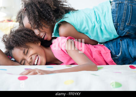 Mixed race sisters playing on bed Stock Photo