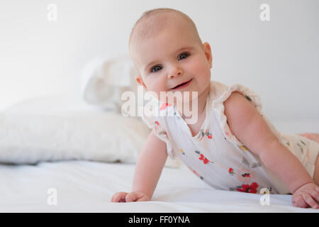 Caucasian baby girl crawling on bed Stock Photo