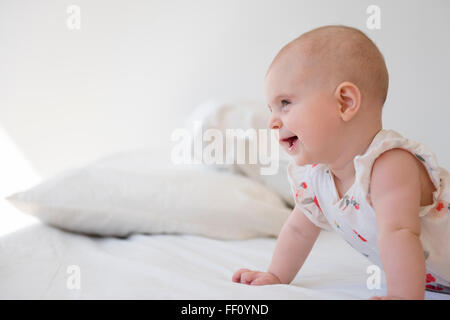 Caucasian baby girl crawling on bed Stock Photo