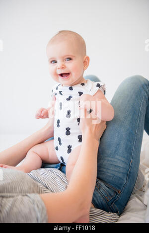 Caucasian mother holding baby daughter on bed Stock Photo