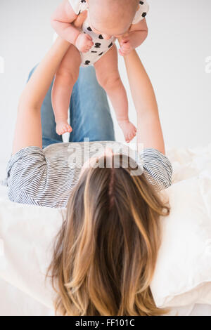 Caucasian mother holding baby daughter on bed Stock Photo
