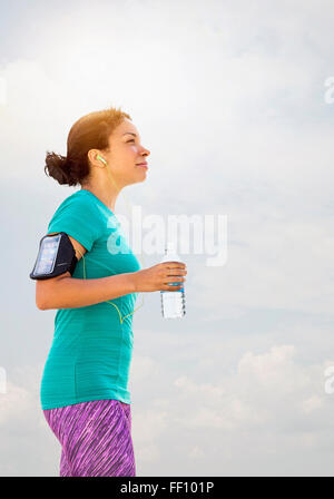 Mixed race runner drinking water outdoors Stock Photo