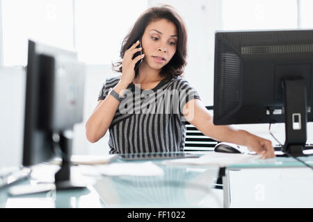 Mixed race businesswoman working at desk Stock Photo