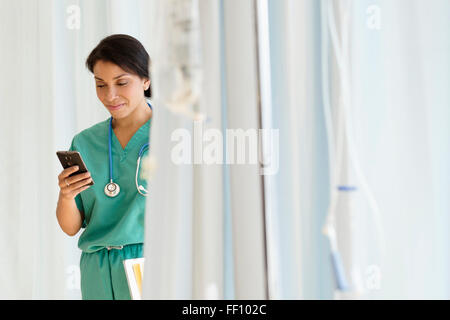 Mixed race nurse using cell phone in hospital Stock Photo