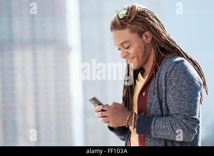 Mixed race man using cell phone outdoors Stock Photo