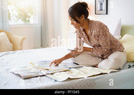 Mixed race woman reading map in bed Stock Photo