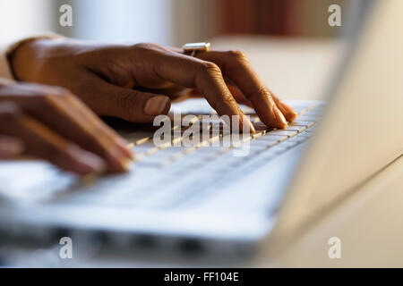 Mixed race woman using laptop at desk Stock Photo