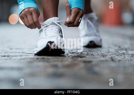 Mixed race runner tying shoelaces Stock Photo