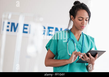 Mixed race nurse using digital tablet in hospital Stock Photo