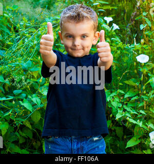 Caucasian boy giving thumbs up in garden Stock Photo