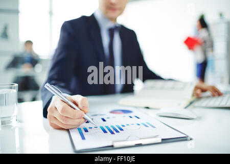 Young businessman pointing at chart in document in office Stock Photo