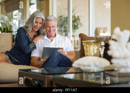 Older Caucasian couple using digital tablet on sofa Stock Photo