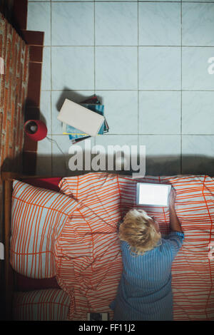 Woman using digital tablet on bed Stock Photo