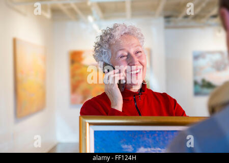 Older mixed race woman using cell phone in art gallery Stock Photo