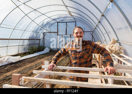 Caucasian farmer standing in greenhouse Stock Photo