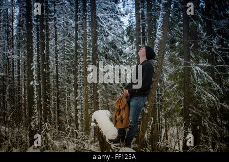 Caucasian hiker standing in snowy forest Stock Photo