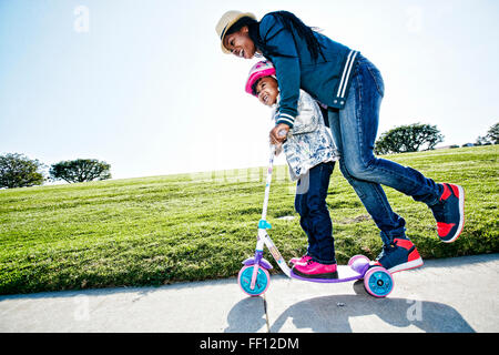 Black mother and daughter riding scooter Stock Photo