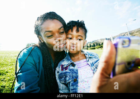 Black mother and daughter taking selfie outdoors Stock Photo