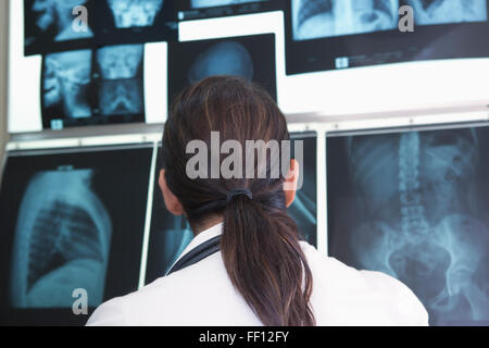 Hispanic doctor examining x-rays in hospital Stock Photo